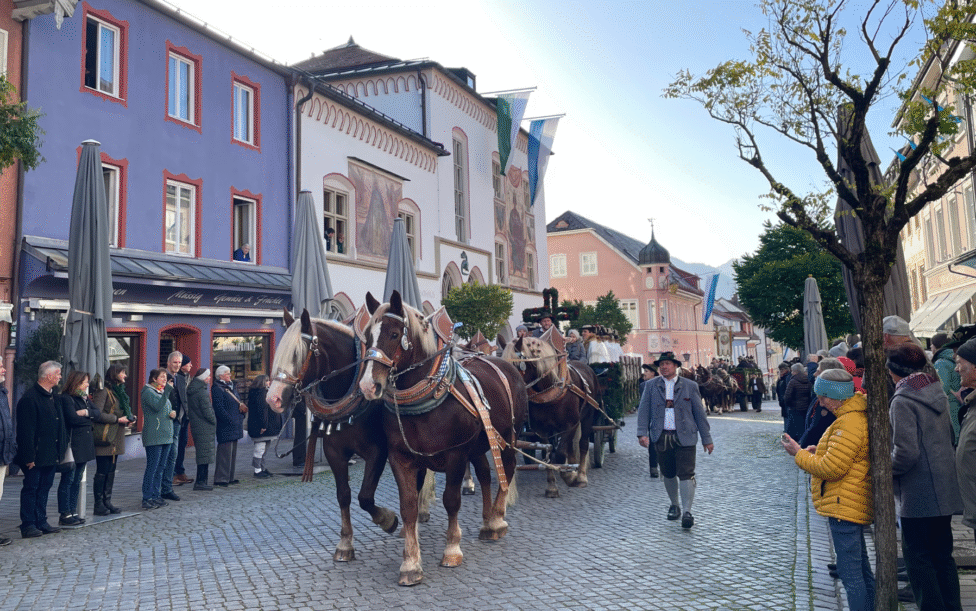 Leonhardi in der Murnauer Fußgängerzone - Ein Pferd zieht eine Kutsche mit Menschen und dem Murnauer Rathaus im Hintergrund.