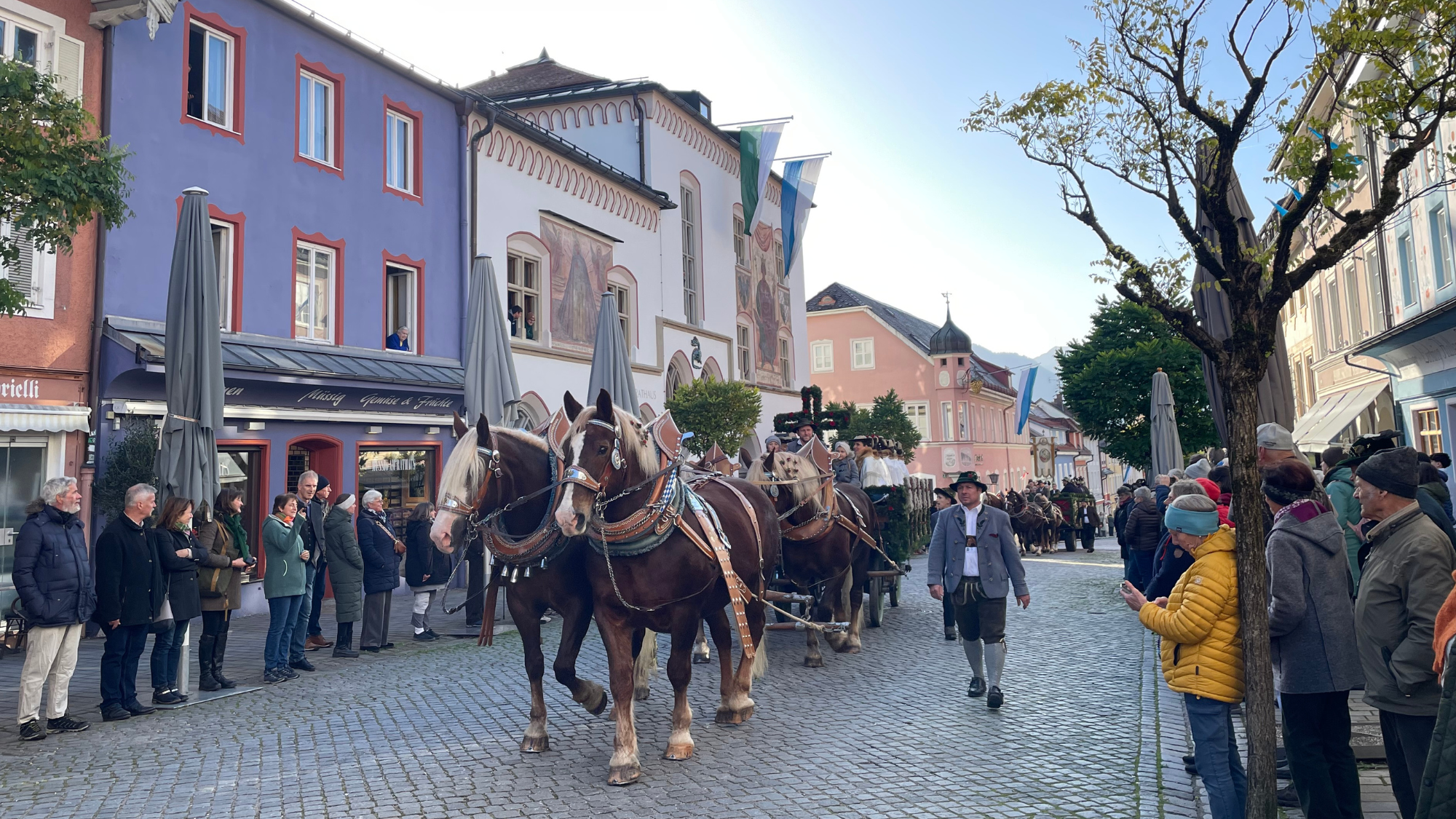 Leonhardi in der Murnauer Fußgängerzone - Ein Pferd zieht eine Kutsche mit Menschen und dem Murnauer Rathaus im Hintergrund.