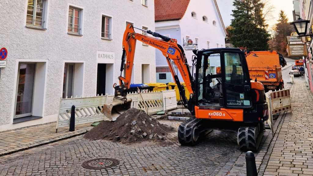 Bau einer Querungshilfe in der Murnauer Schloßbergstraße - ein kleiner Bagger vor dem Rathausnebeneingang