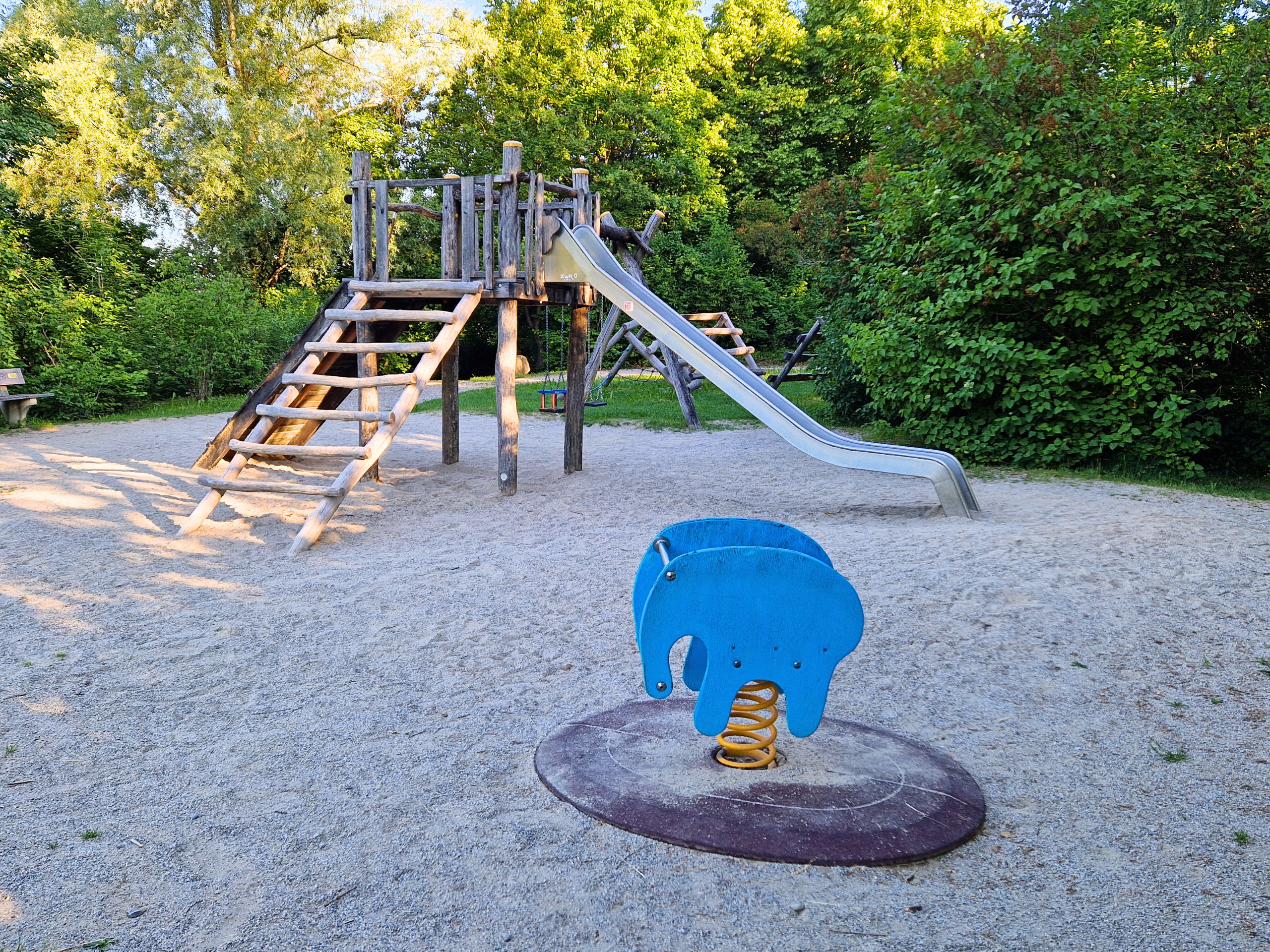 Blick auf den Spielplatz im Murnauer KulturPark mit Klettergerüst und Schaukeln und Wipptier.