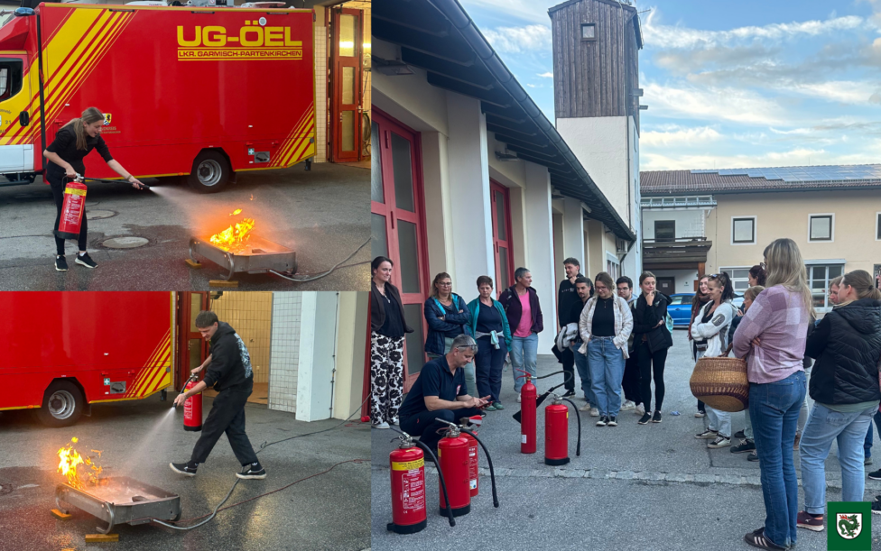 Eine Gruppe von Personen steht vor einem Gebäude und nimmt an einer Fortbildung zum Brandschutzhelfer teil; mehrere rote Feuerlöscher sind auf dem Boden platziert.